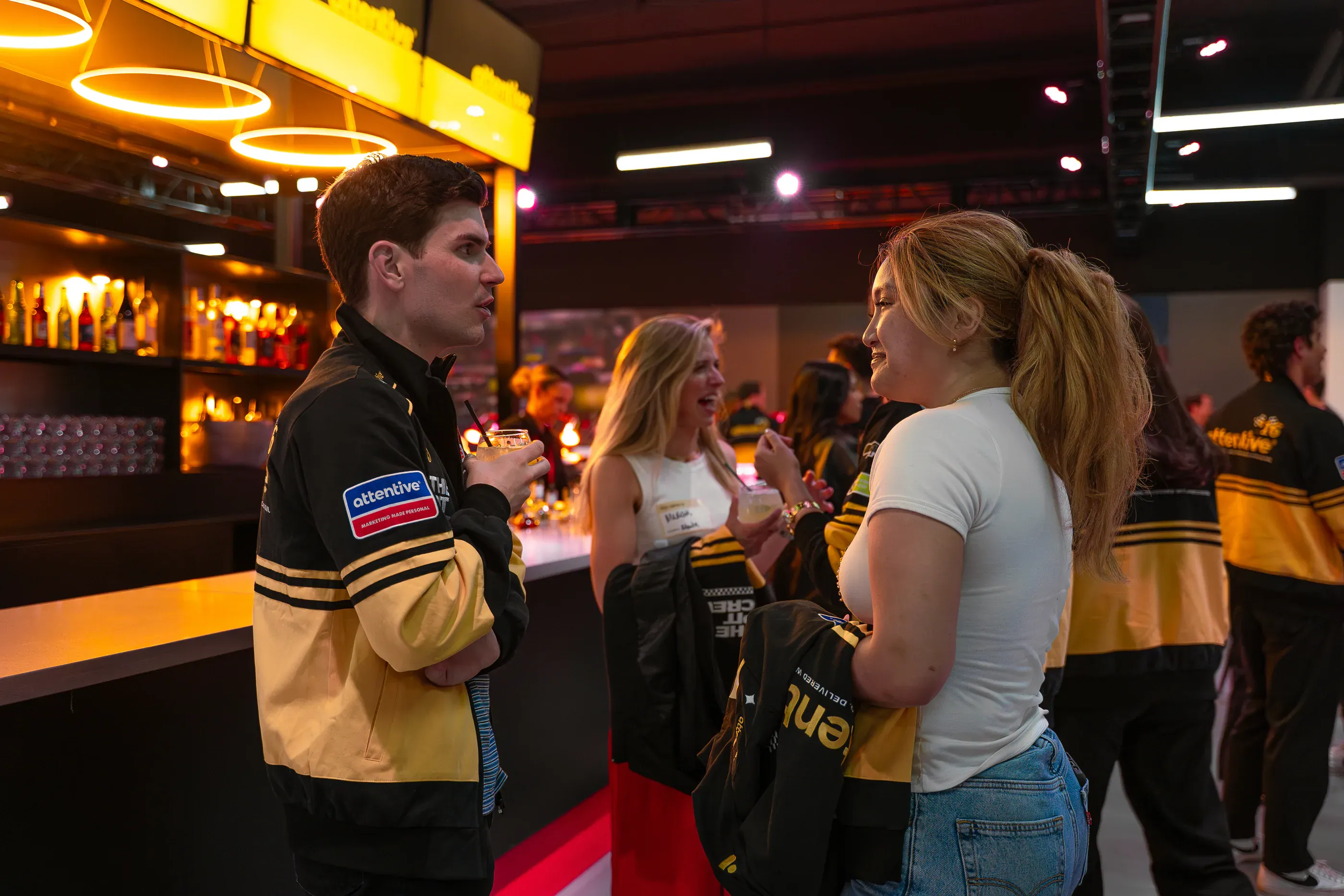 Two people talk beside an Attentive-branded event vehicle.
